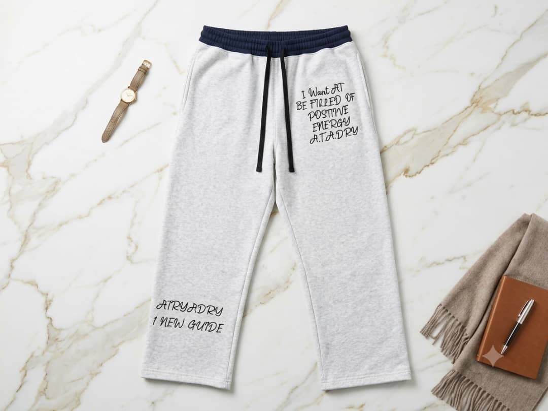 Gray joggers with black text prints and navy waist on marble.