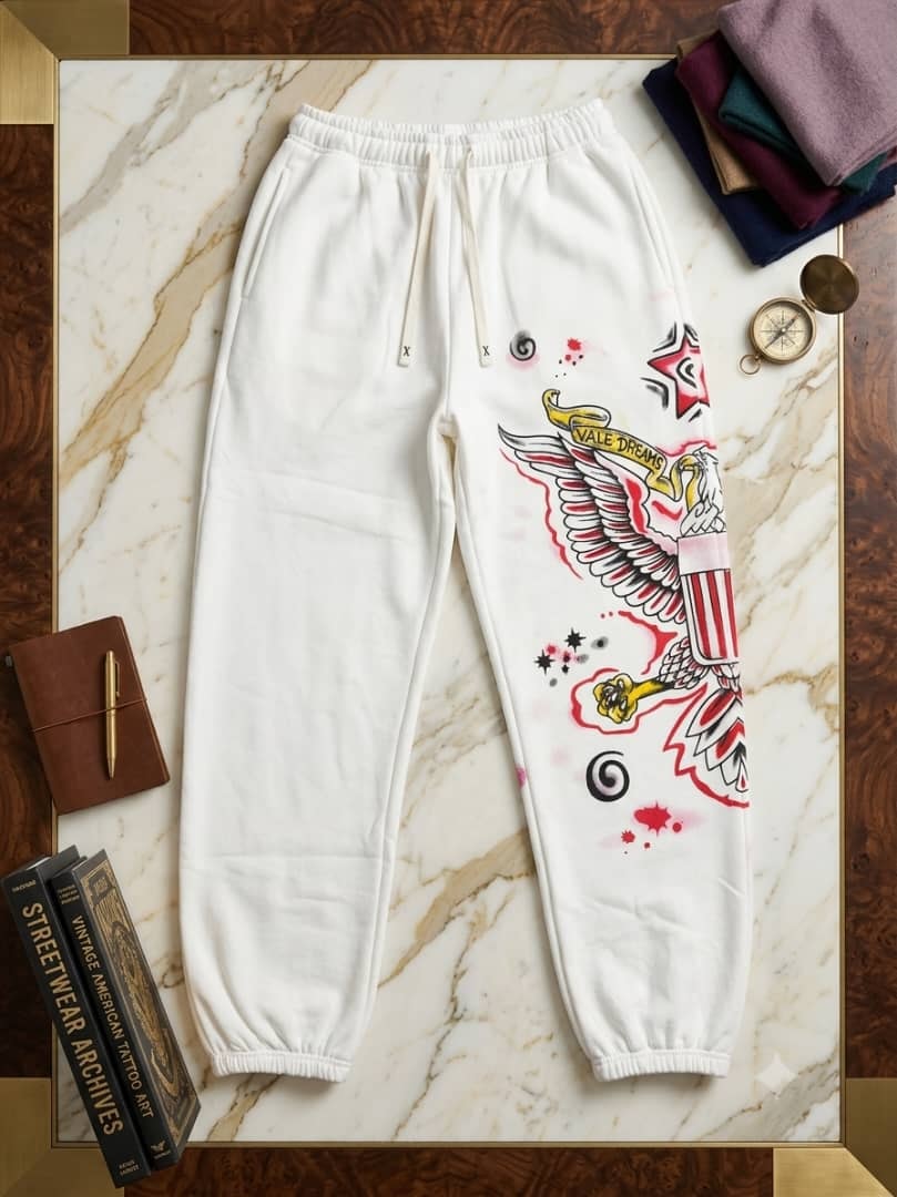 White joggers with large eagle graphic on marble surface.