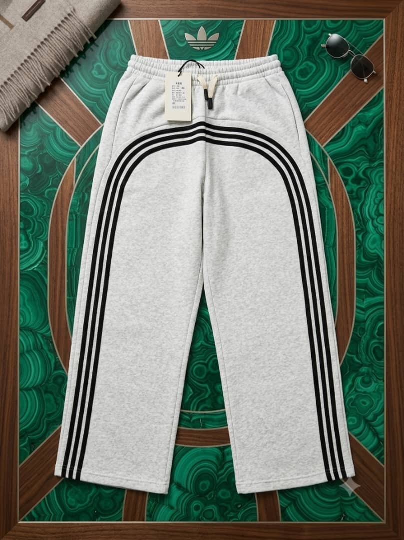 Gray joggers with black arched stripes on green and wood background.