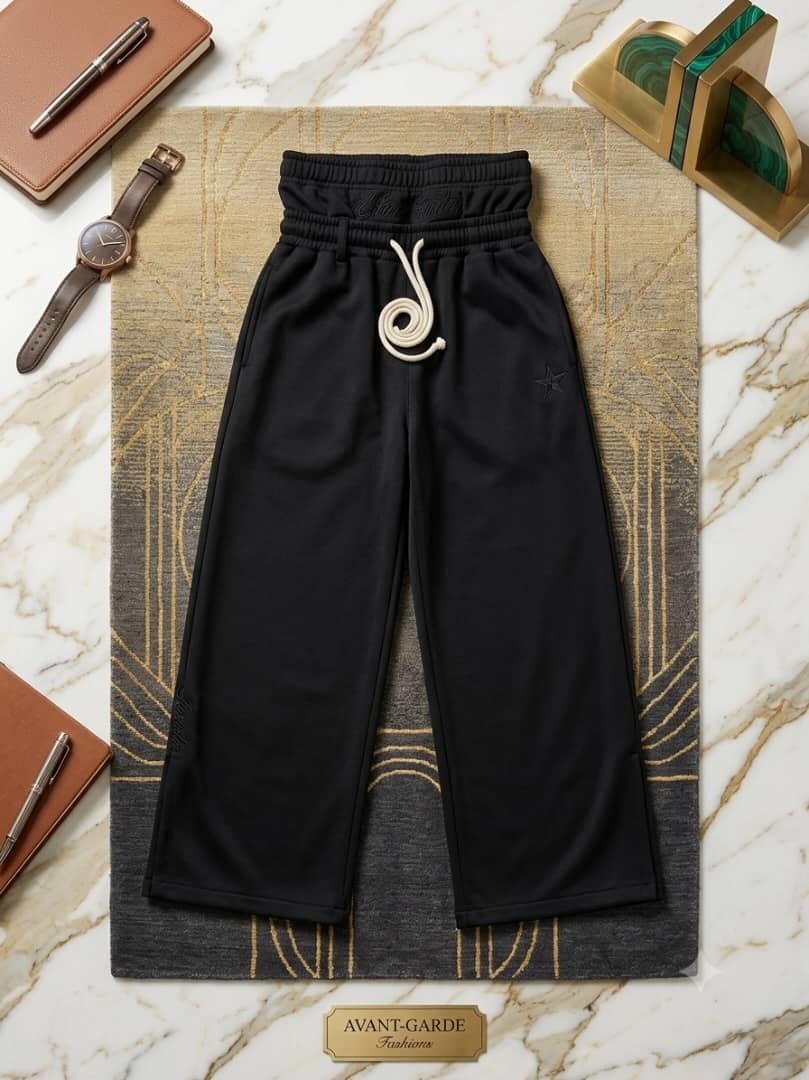 Black joggers with star embroidery on patterned rug.