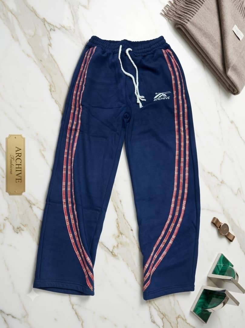 Navy blue joggers with plaid stripes and ARCHIVE logo on marble.