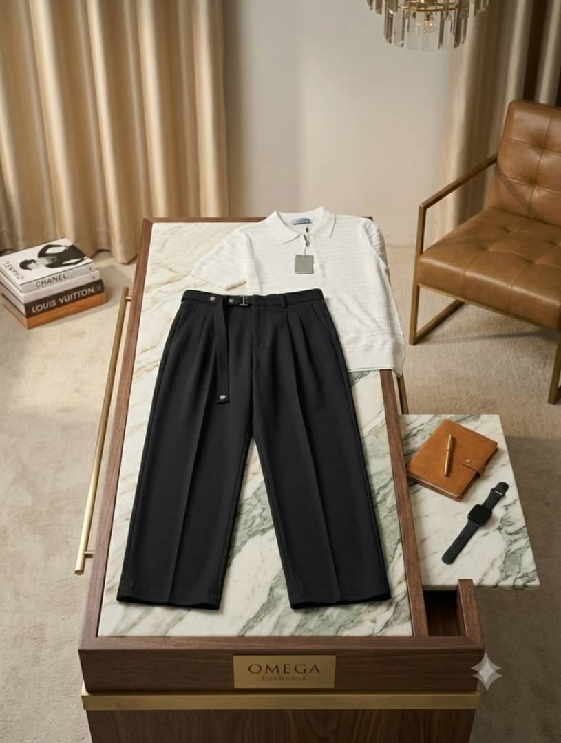 White textured polo shirt and black pleated pants displayed on marble table with Omega sign.