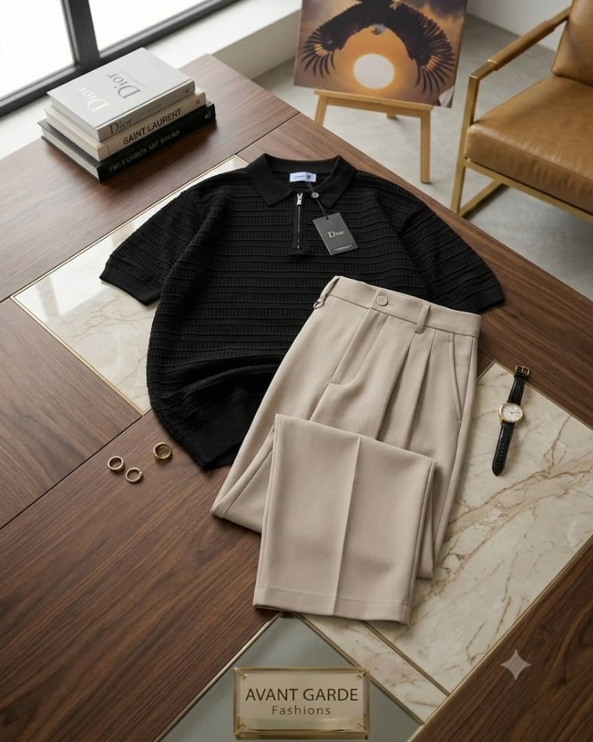 Black textured zip polo and beige pleated pants flat lay with accessories and Avant Garde sign.