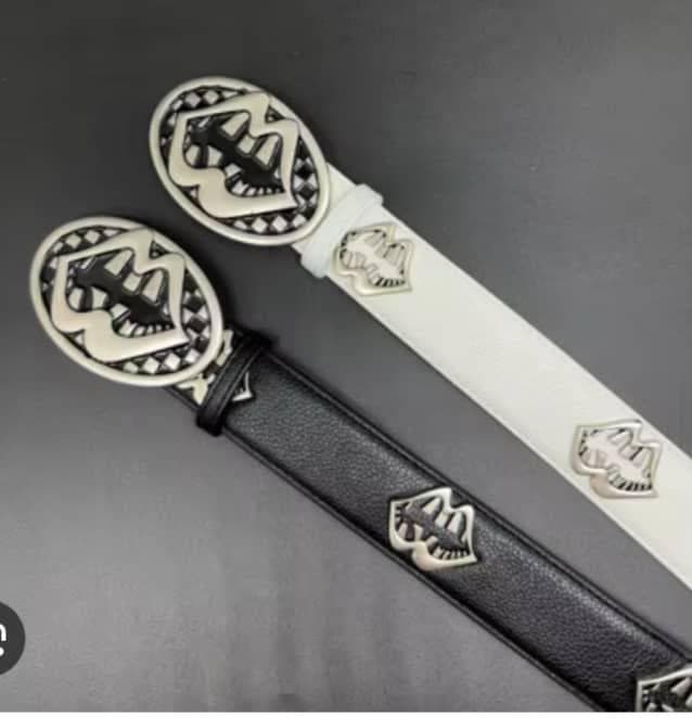 Black and white leather belts with large oval silver crest buckles and repeating emblems shown together.