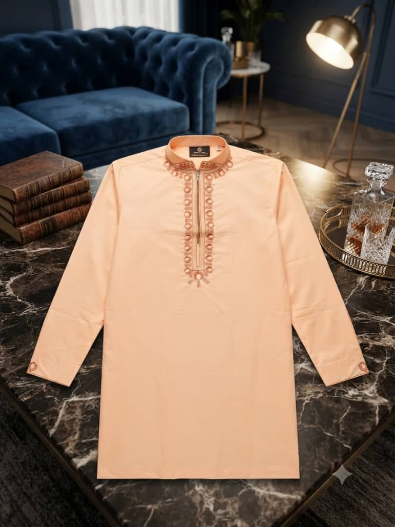Peach long sleeve jalabia with gold embroidery on marble table.
