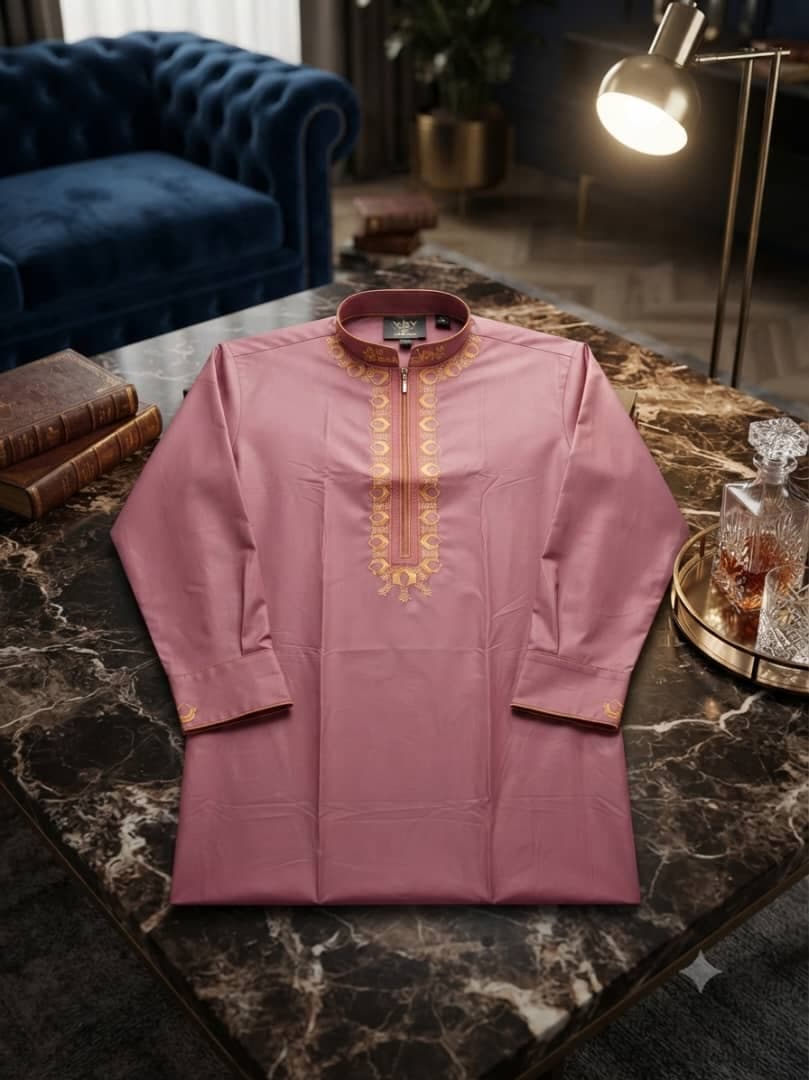 Pink long sleeve jalabia with gold embroidery on marble table.