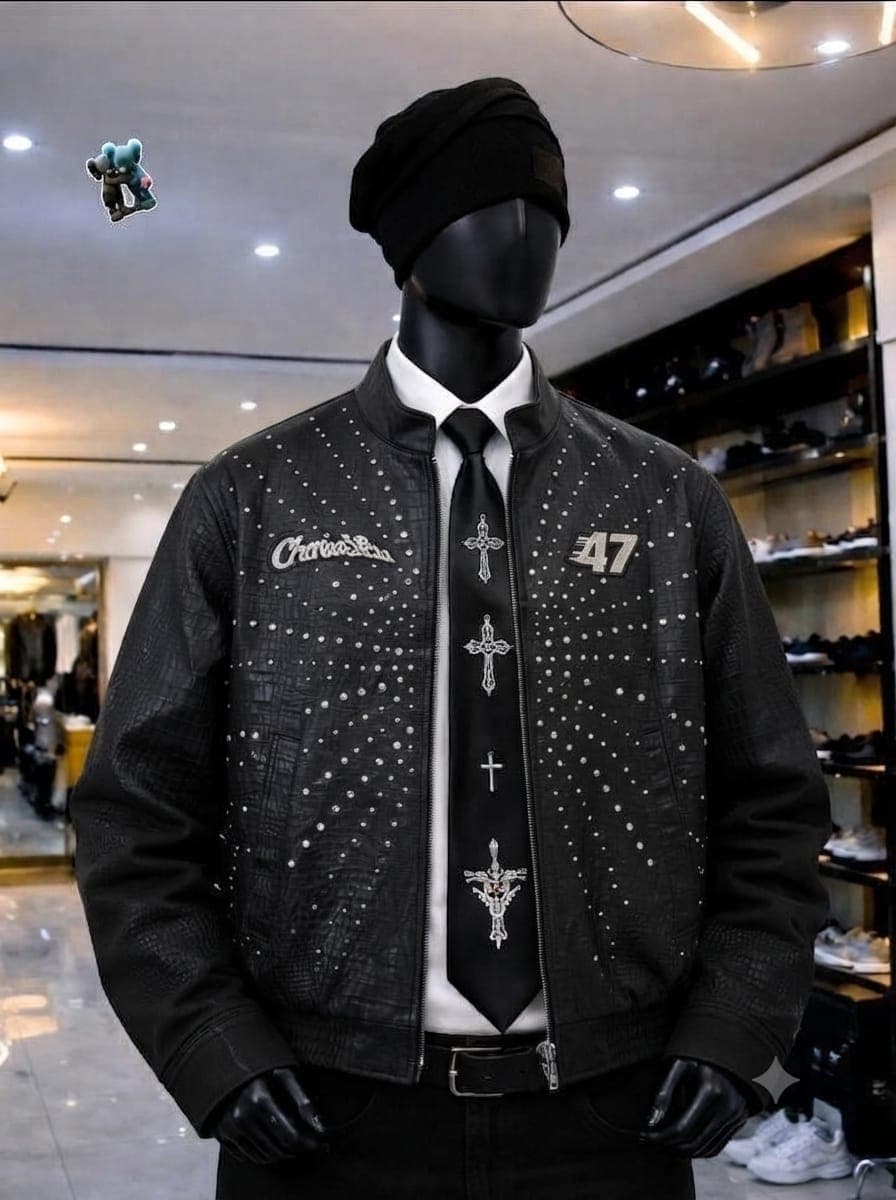 Black studded bomber jacket on mannequin with graphics and crosses.