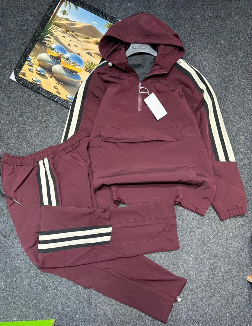 Maroon hooded cargo tracksuit laid flat showing quarter-zip top and striped pants.