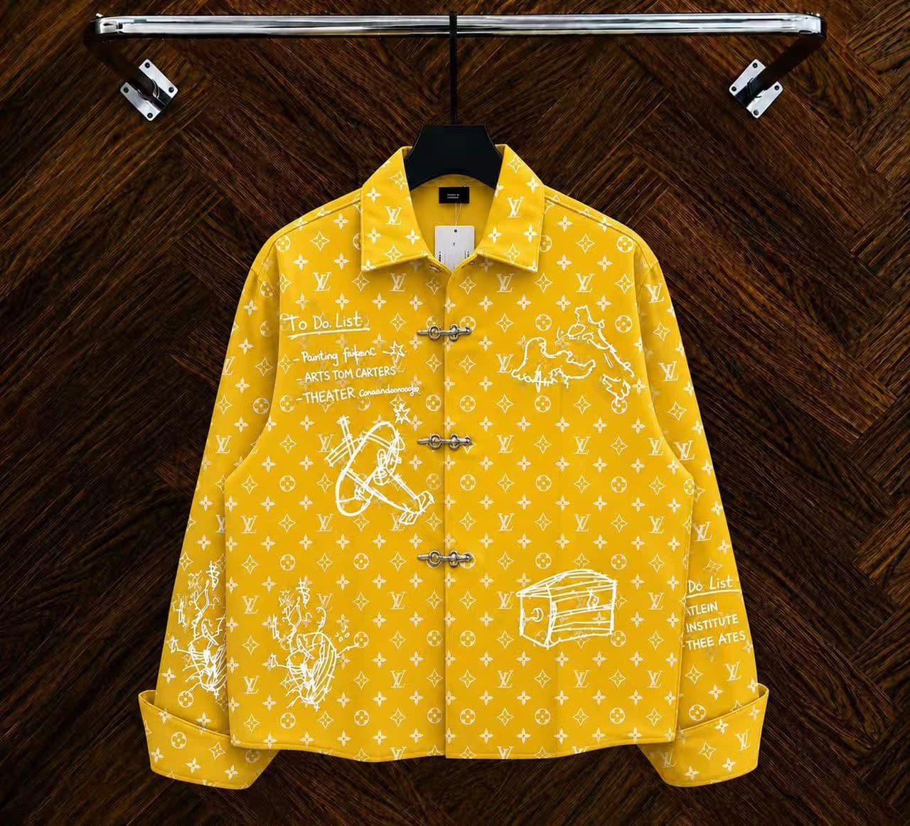 Yellow monogram sketch toggle jacket hanging on rack with white drawings.