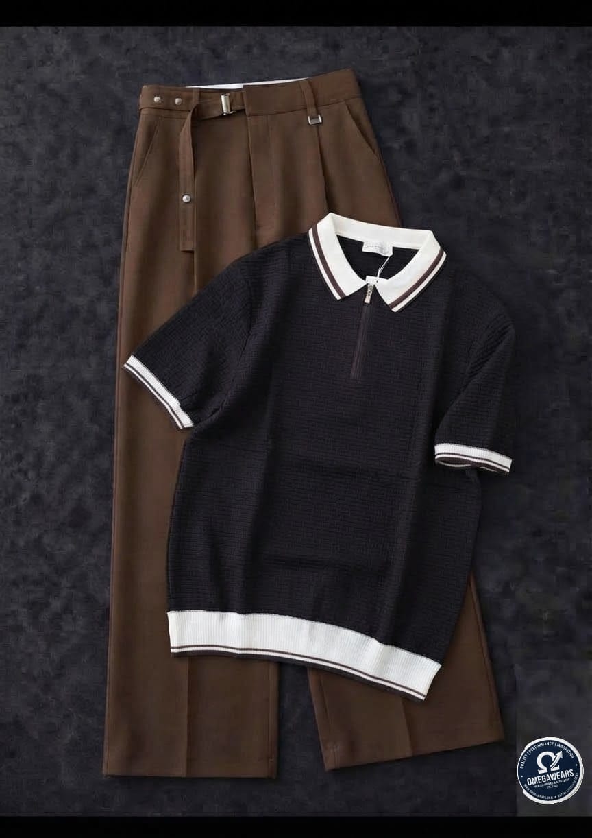 Black knitted polo with white trim and brown pleated trousers.