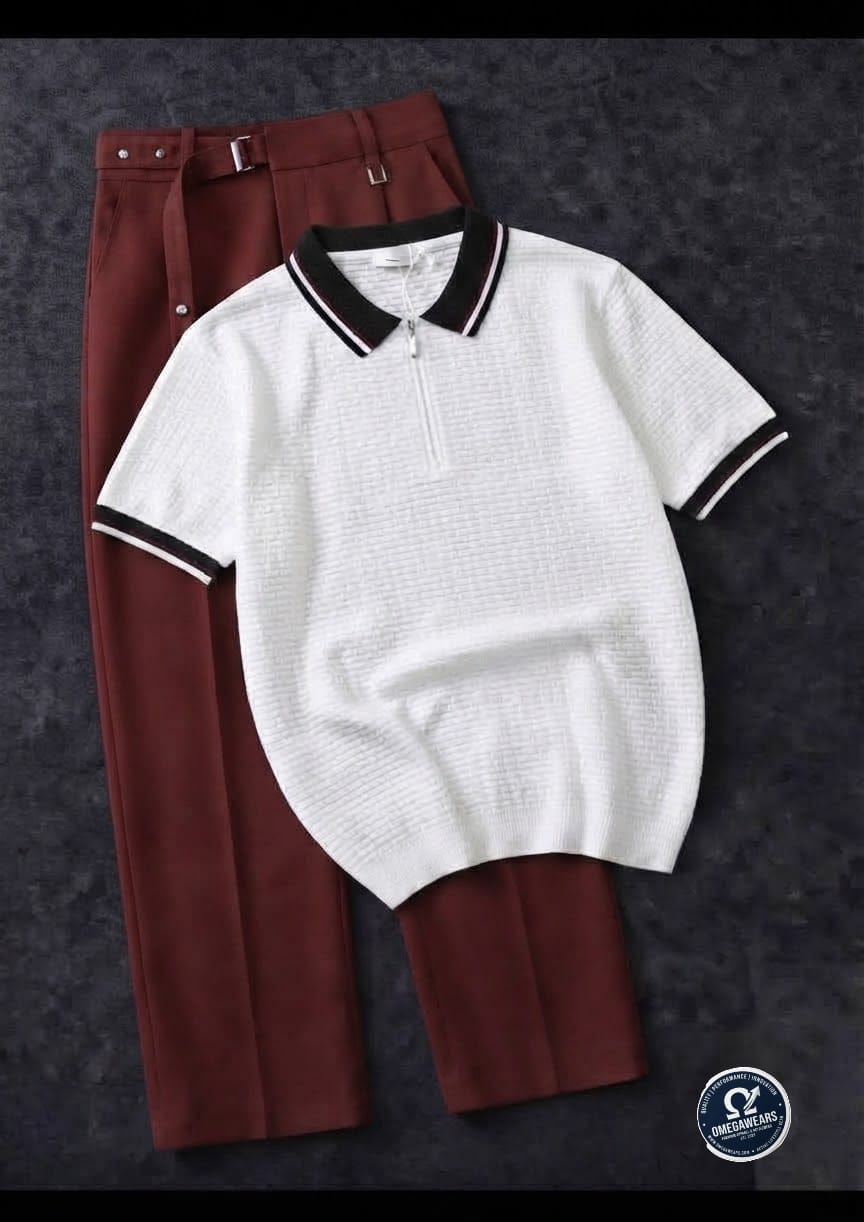 White knitted polo with black trim paired with burgundy trousers.