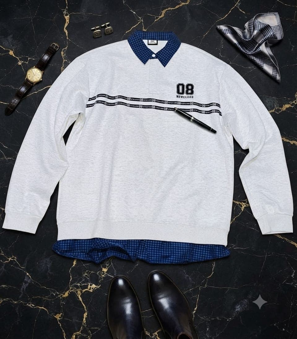 White sweatshirt with blue checkered collar, black logo band across chest, styled with watch, pen and shoes on dark marble.