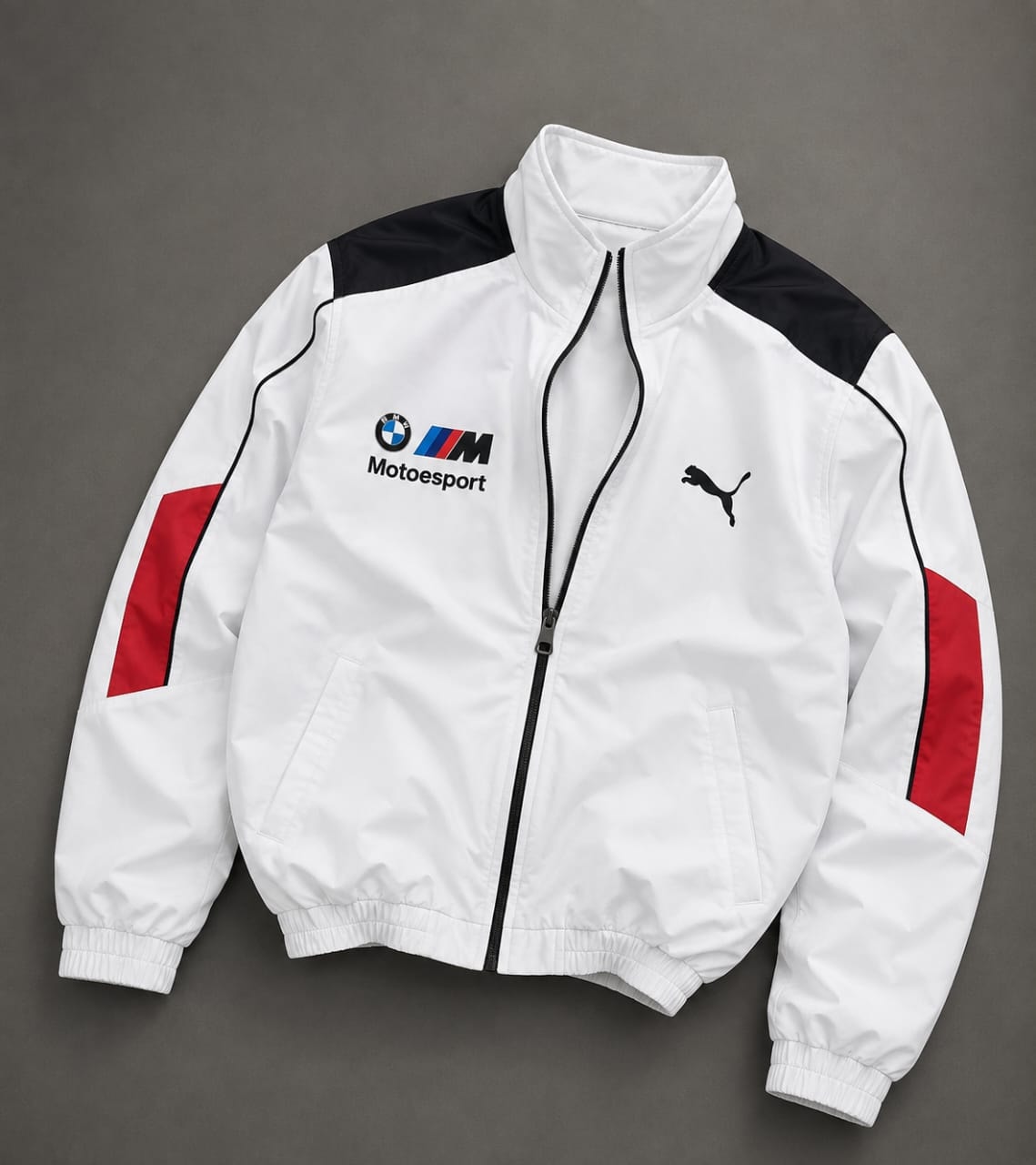 White Puma BMW M Motorsport track jacket with black shoulders and red sleeve panels.