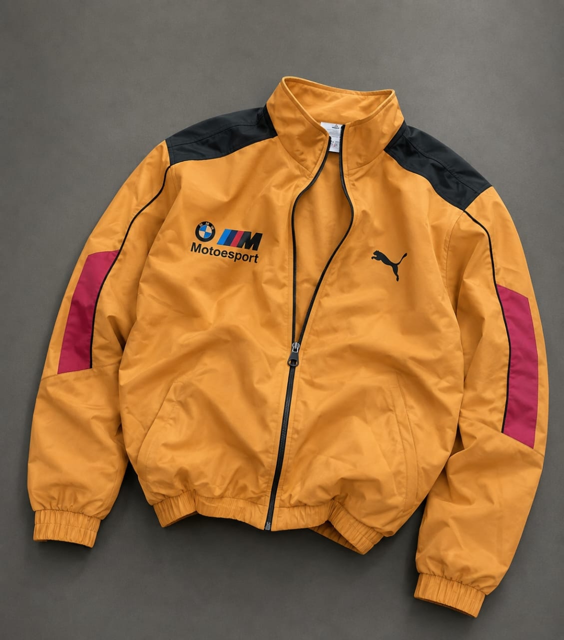 Yellow Puma BMW M Motorsport track jacket with black shoulders and magenta sleeve stripes.