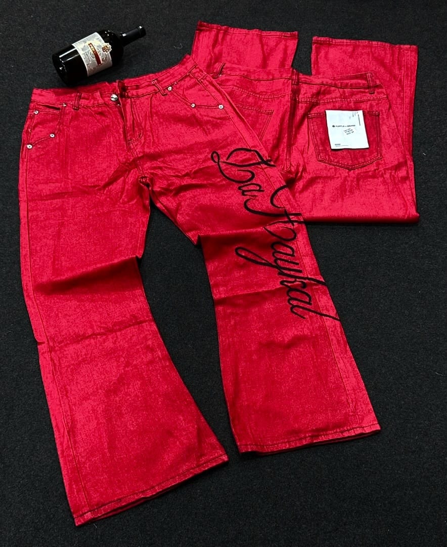 Light blue flare jeans with red embroidery on back pocket, hanging on a clothing rack.