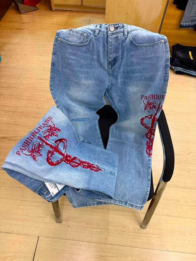 Light blue jeans with red snake, palm tree, and FASHION JEANS embroidery on legs.