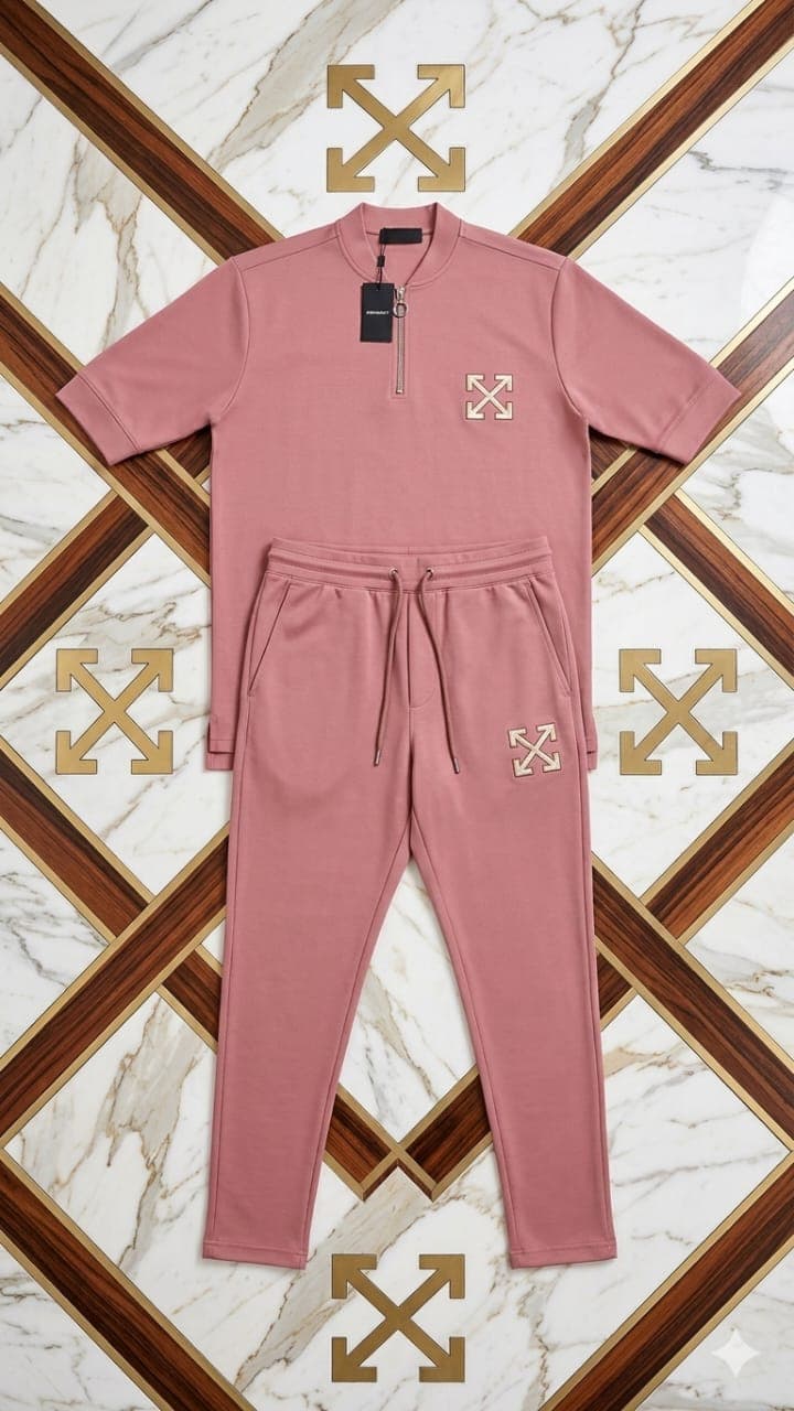 Dusty pink quarter-zip short sleeve top and jogger pants with embroidered details on marble background.
