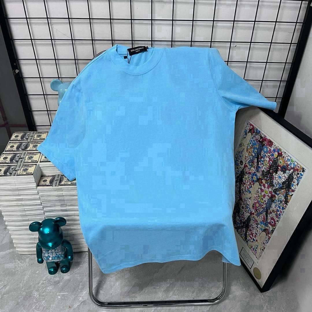 Light blue pixel patterned t-shirt displayed on chair with money stacks and artwork.