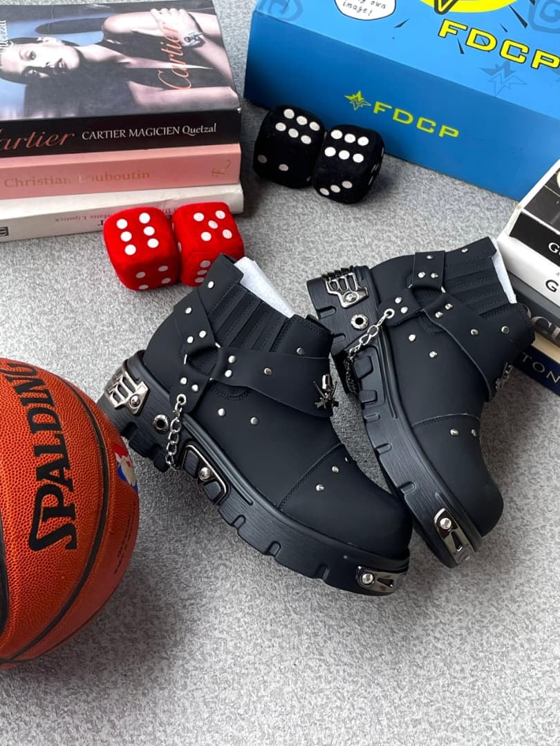 Black studded platform boots with chains surrounded by fashion books, dice and basketball.