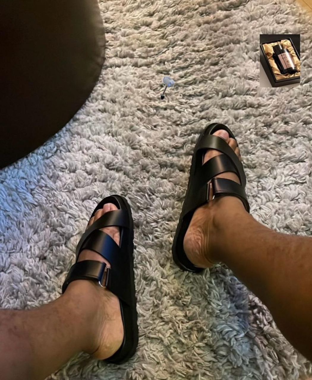Black multi-strap sandals worn on feet on grey rug with small product inset image.