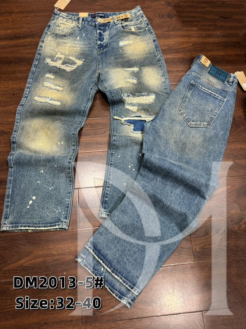 Front and back of blue baggy jeans with white splatters, large rips and Zuaideren tags on wooden floor.