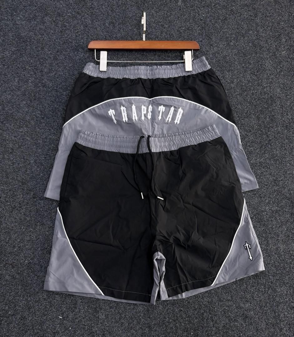 Black and gray Trapstar logo colorblock shorts on hanger.