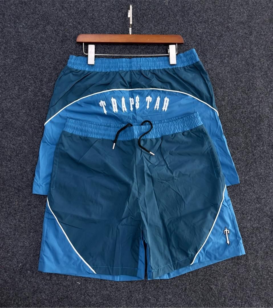 Blue Trapstar logo colorblock shorts on wooden hanger.