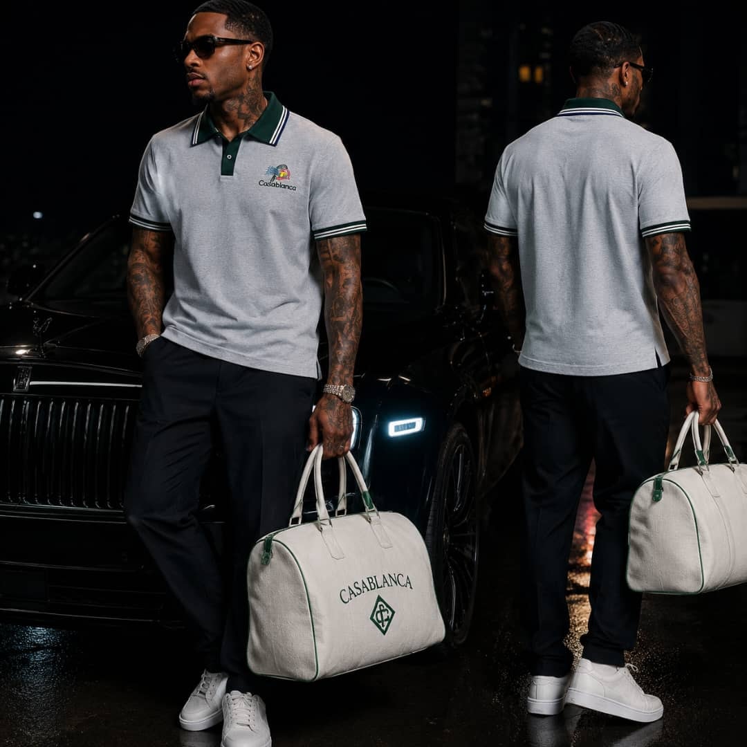 Man wearing gray green-trim polo shirt with bag in front of luxury car at night.