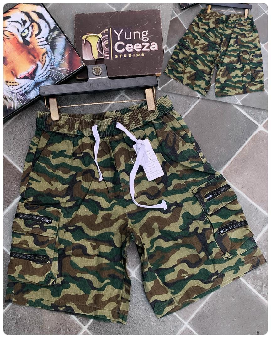 Camouflage cargo shorts with multiple zippered pockets, drawstring waist, and XL tag displayed on tiled floor.