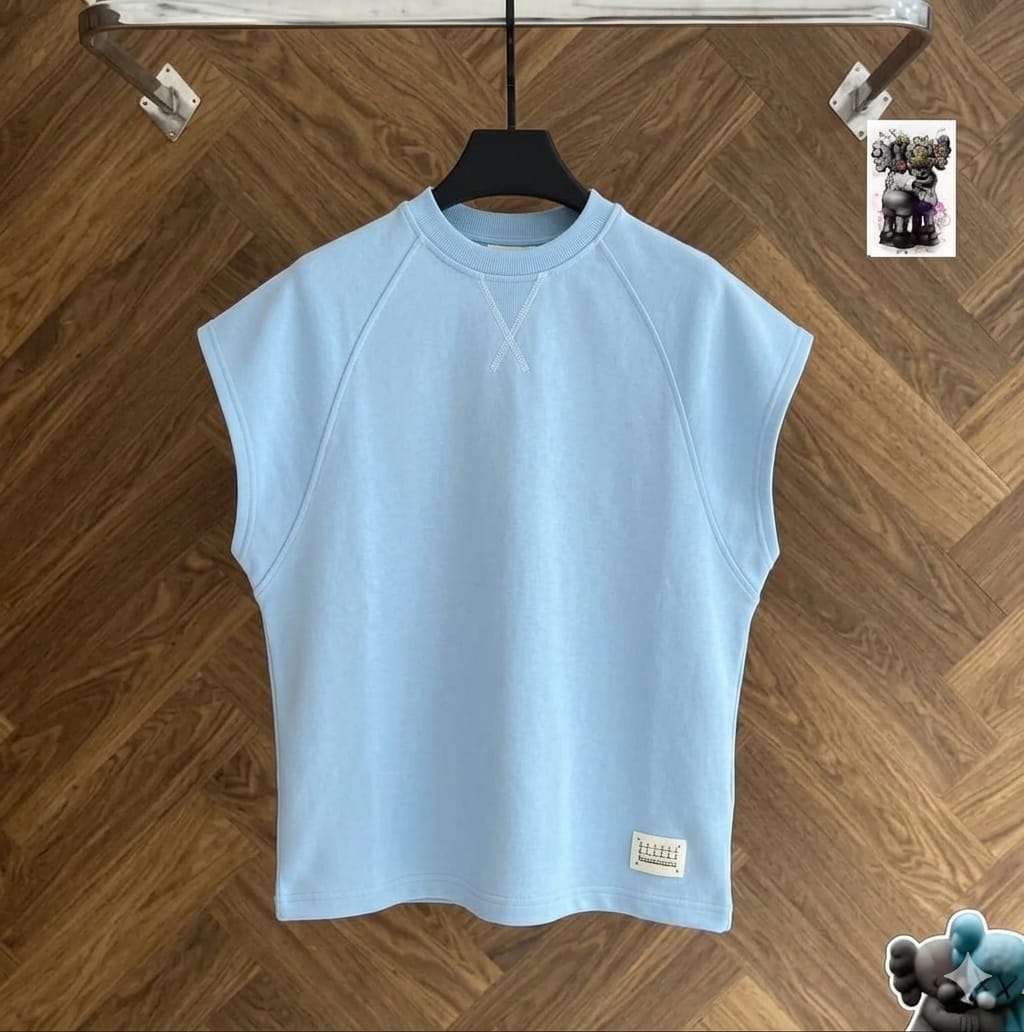 Light blue raglan armless top on black hanger against wood floor.