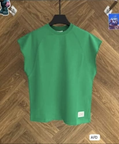 Green raglan armless top on black hanger against wood floor.
