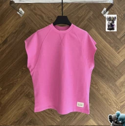 Pink raglan armless top on black hanger against wood floor.