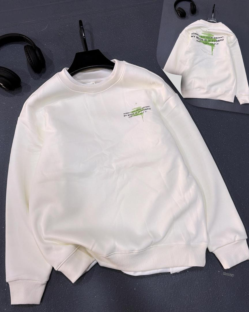 White crewneck sweatshirt with green Scorpio moon text graphic on chest.