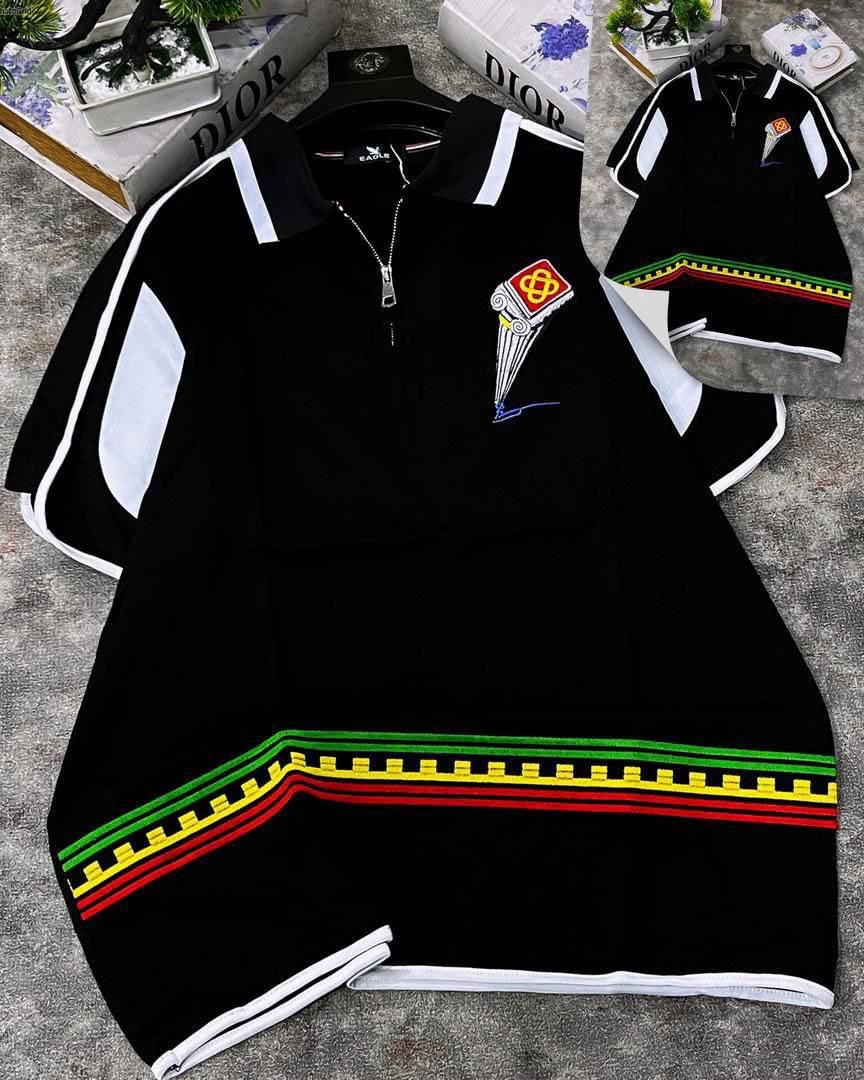 Black polo shirt displaying striped hem and cuffs with white contrast and pillar motif embroidery.