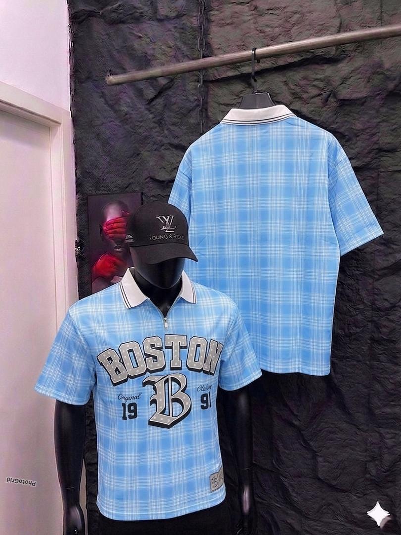 Mannequin in light blue plaid polo shirt with Boston graphic, back view hanging on rack.