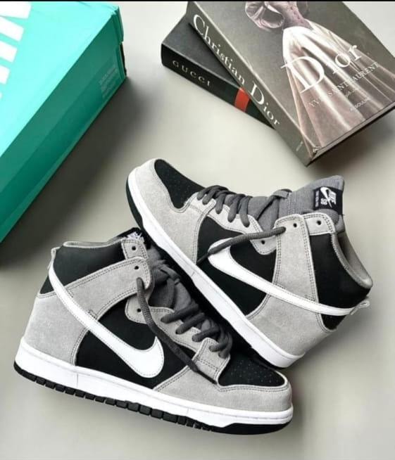 Nike Dunk High sneakers in grey suede and black leather with white sole and swoosh, shown with book and box.