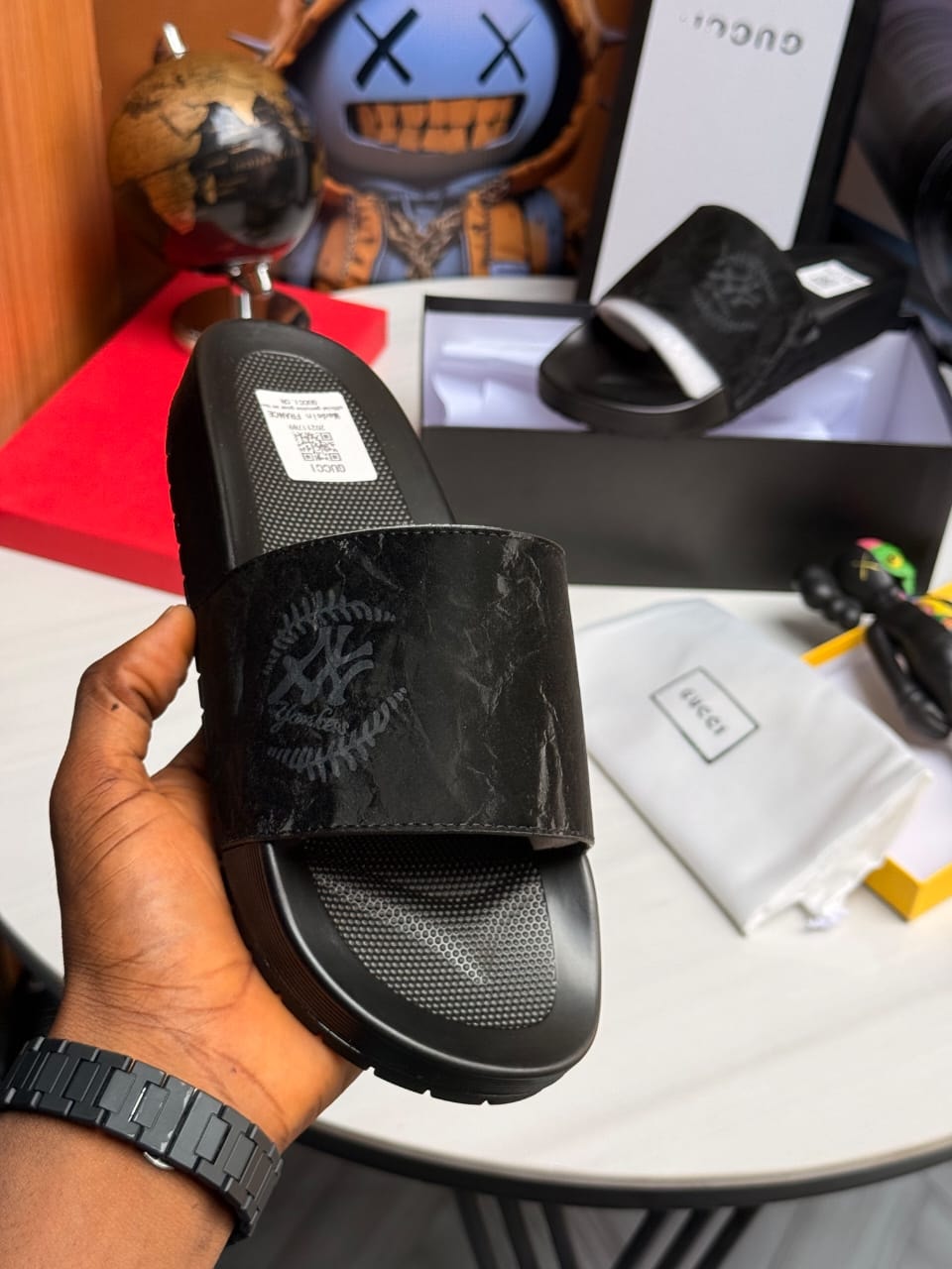 Black Gucci slides with embossed logo and textured strap.