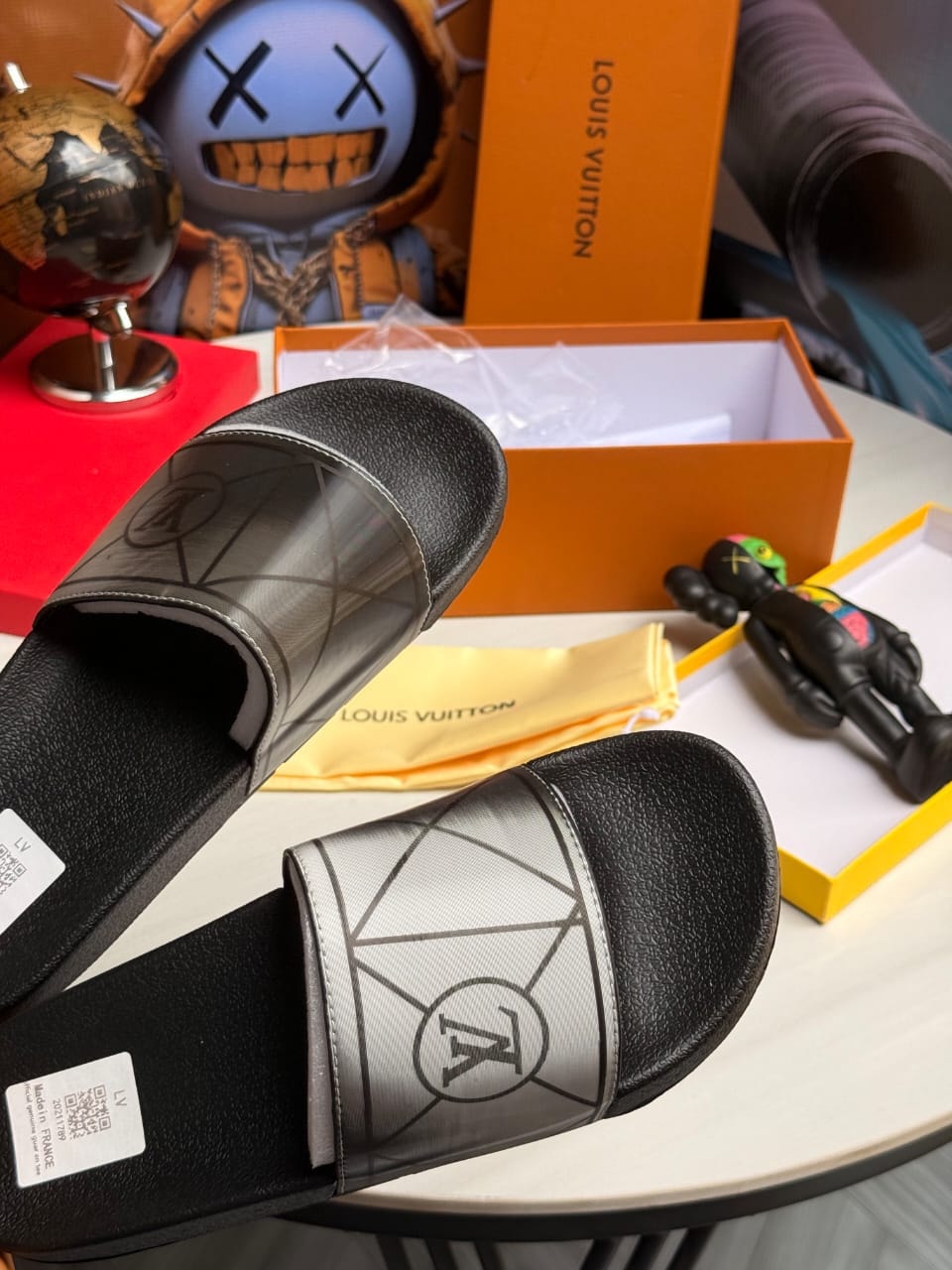 Black Louis Vuitton slides with silver geometric LV monogram pattern and branding.