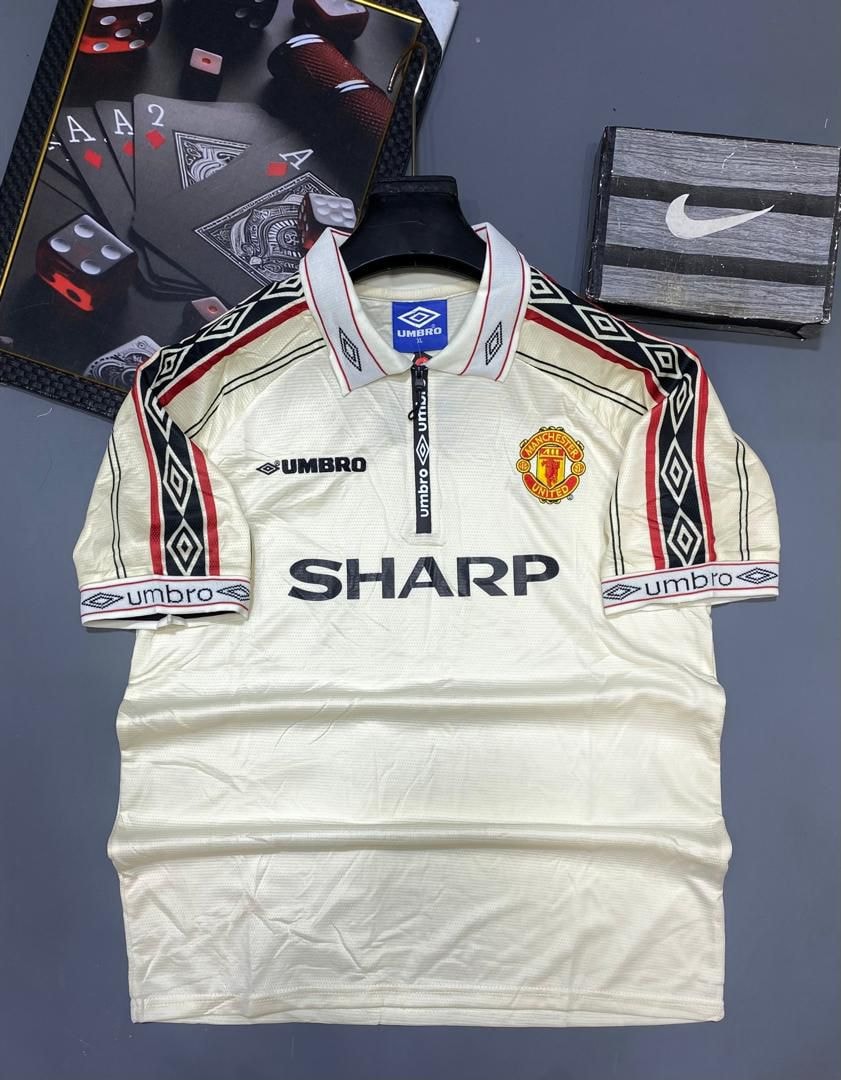 Cream Umbro Manchester United retro jersey with Sharp sponsor on display.