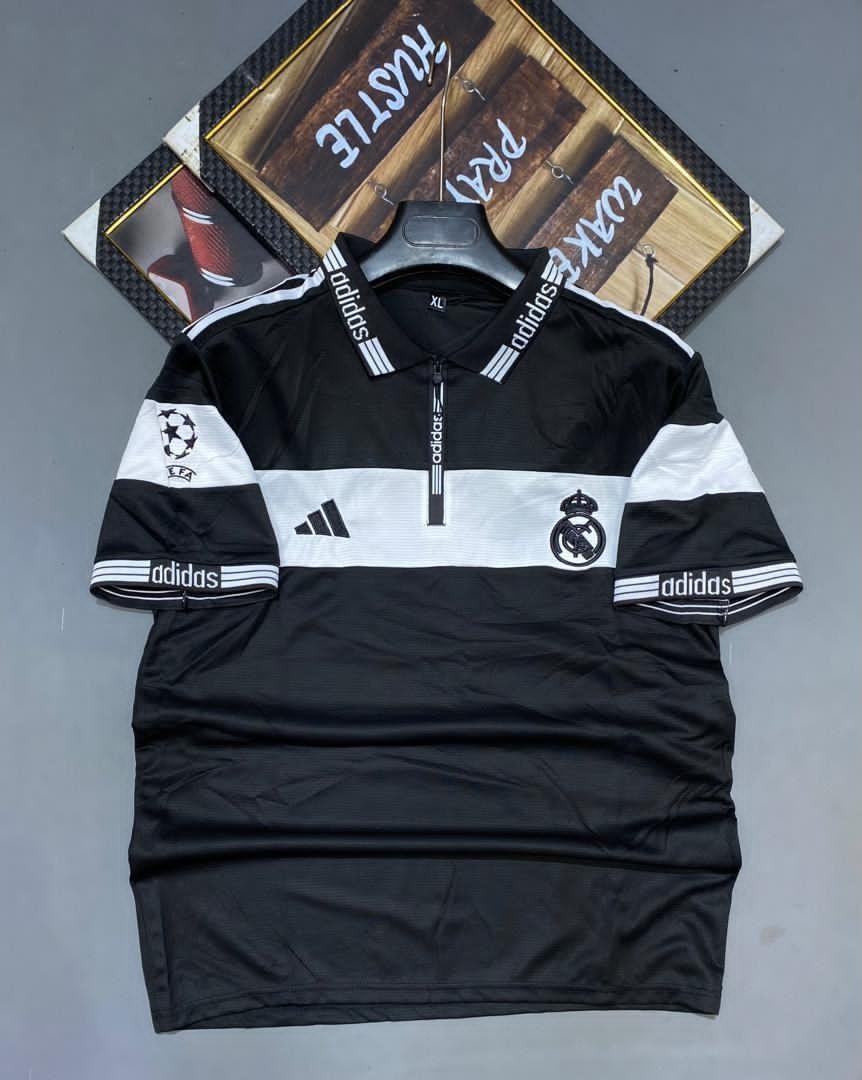 Black and white Adidas Real Madrid soccer jersey on hanger with logos and crest.