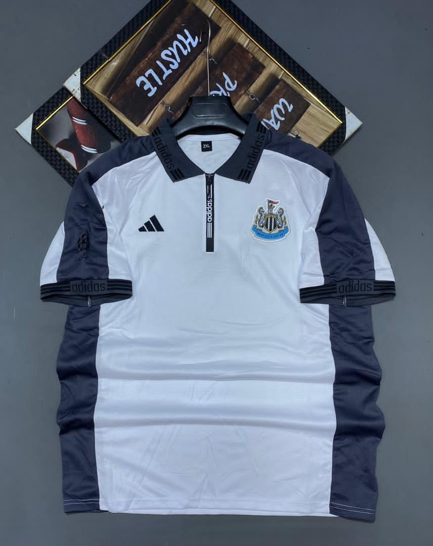 White and navy Adidas Newcastle United soccer jersey on hanger showing front with crest.