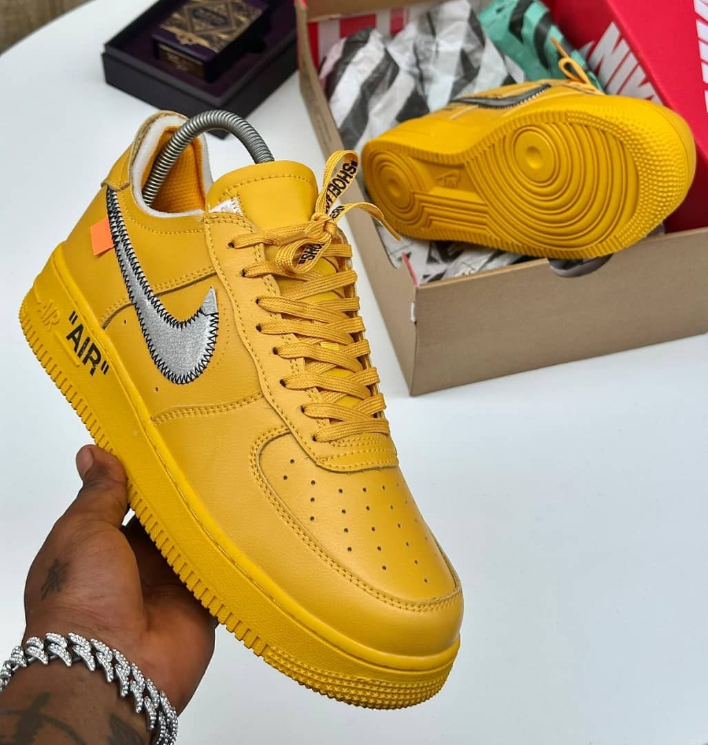 Yellow Nike Air Force 1 sneaker held in hand showing side profile and sole.