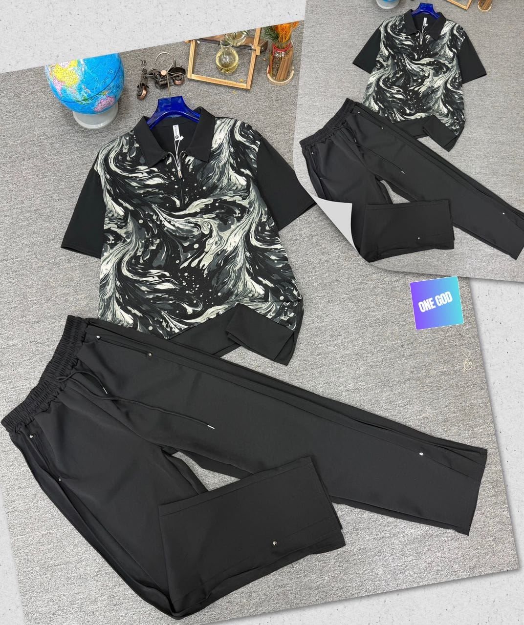 Black two-piece set with white and black marble print polo shirt and black trousers.