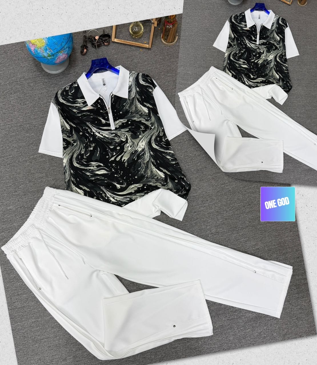 White two-piece set with black and white marble print polo shirt and white trousers.