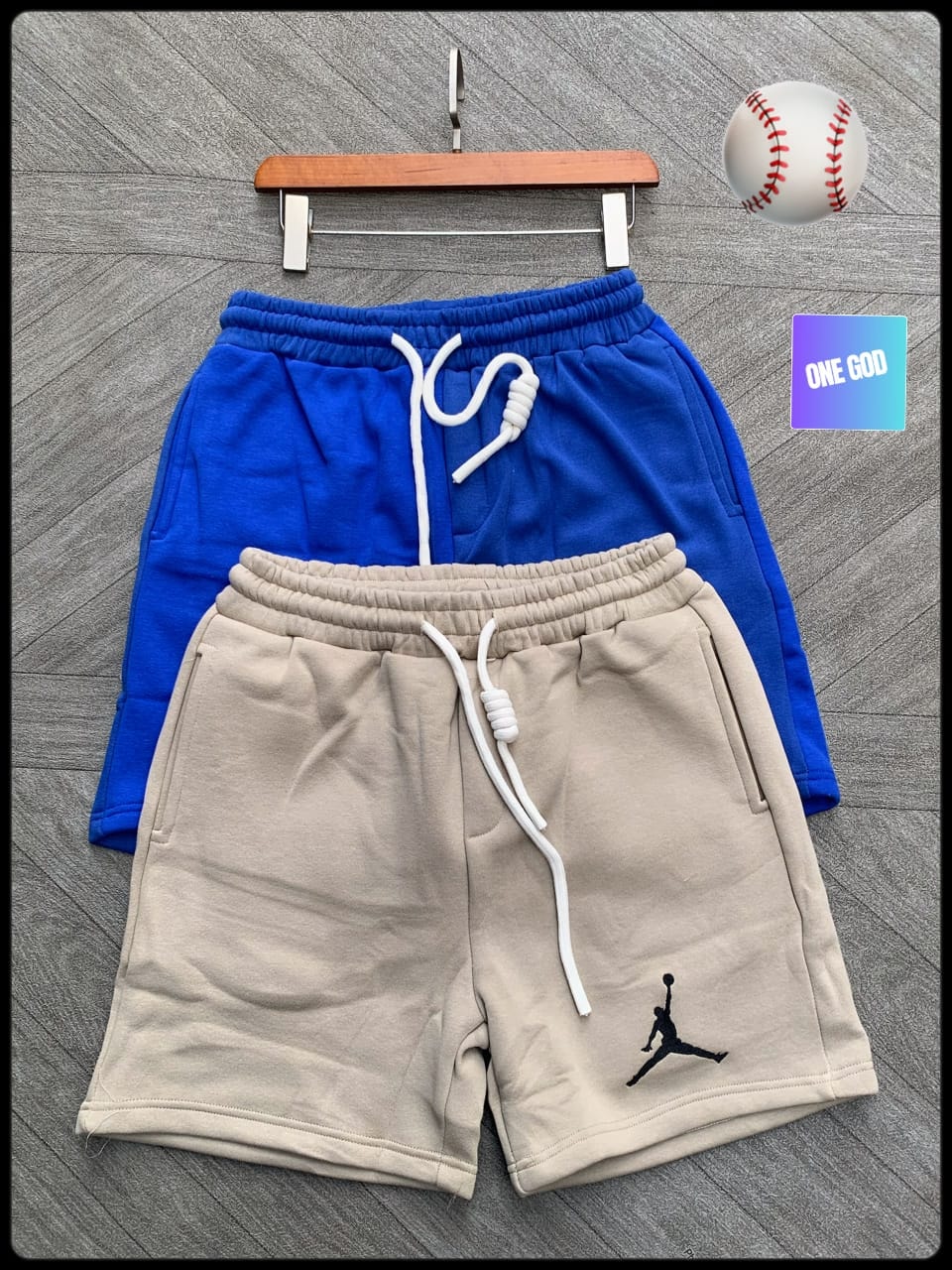 Beige fleece shorts with black Jumpman logo and blue pair on hanger.
