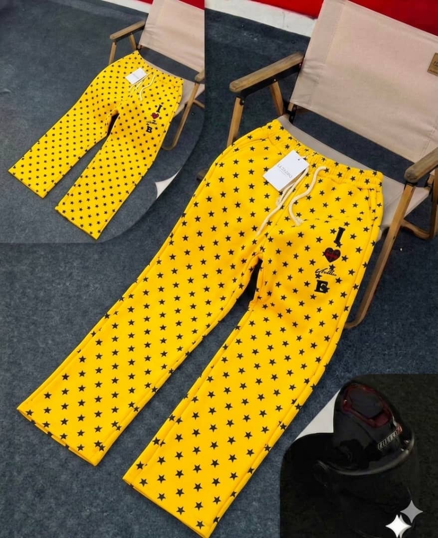 Yellow star-patterned joggers with black stars, drawstring waist and thigh embroidery.