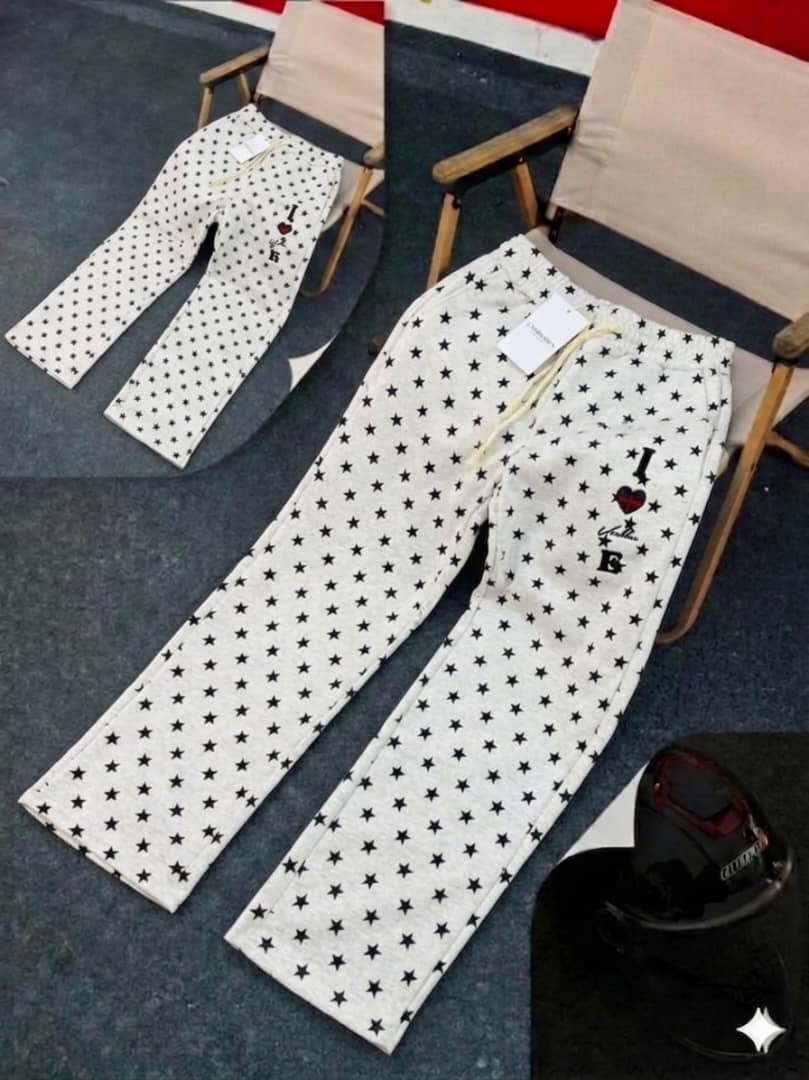White star-patterned joggers with black stars, drawstring waist and thigh embroidery.