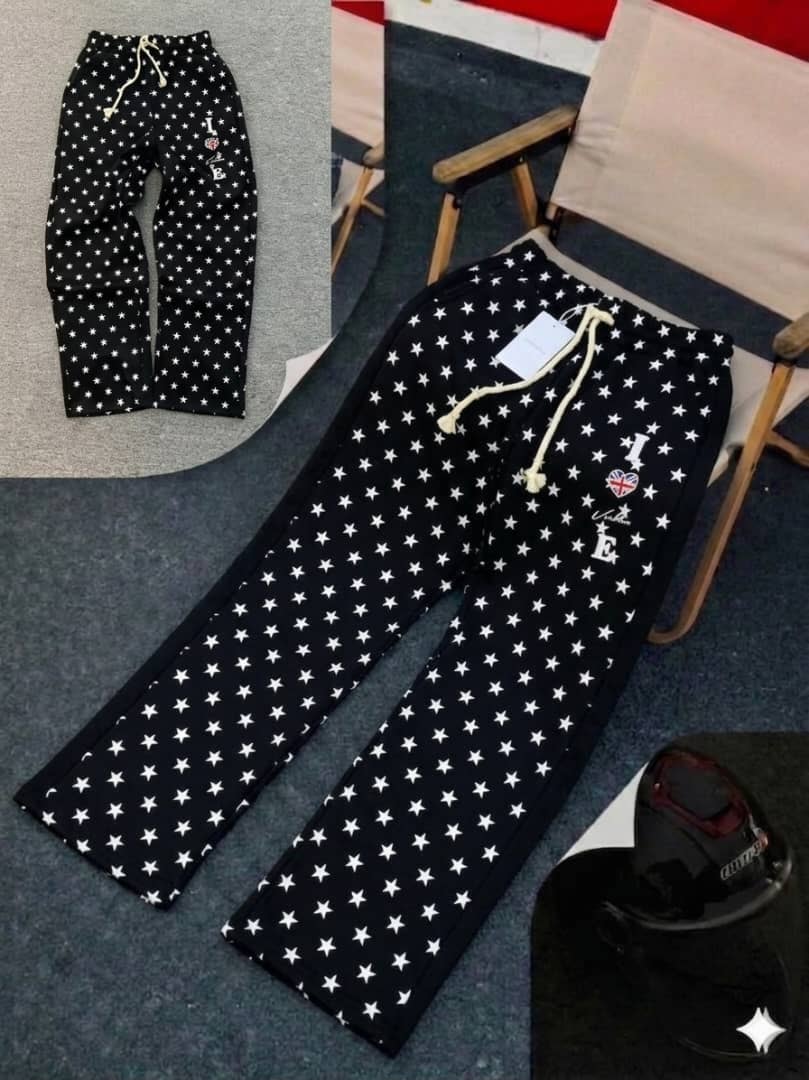 Black star-patterned joggers with white stars, drawstring waist and thigh embroidery.