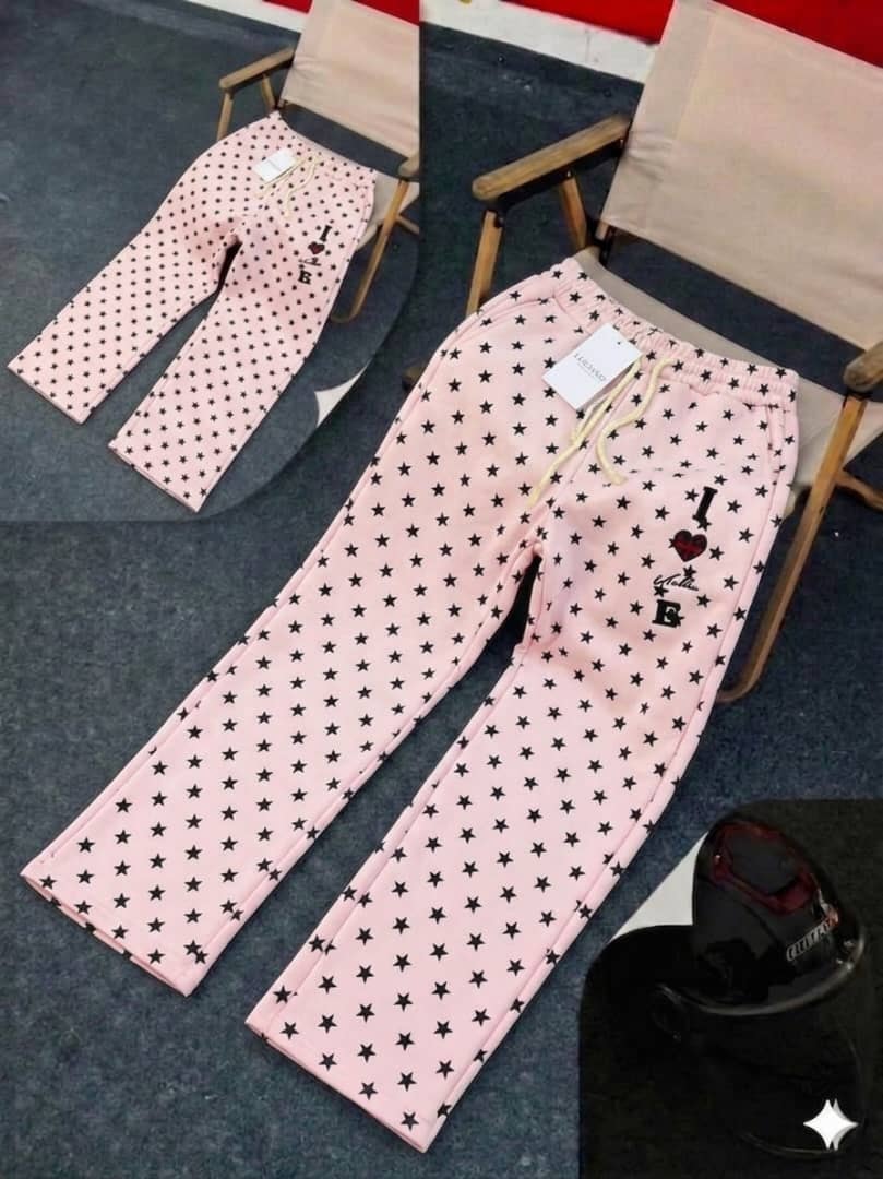 Pink star-patterned joggers with black stars, drawstring waist and thigh embroidery.
