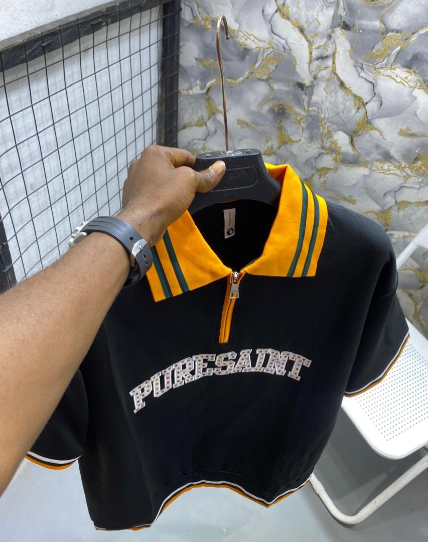 Black short-sleeve polo shirt with yellow collar, green stripes and PURESAINT graphic on chest.